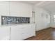 Kitchen area with white cabinetry, modern backsplash, stainless steel appliances and access to living room at 3632 E Kaley Ave, Orlando, FL 32812