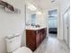 Bathroom features a double vanity, wood-look tile flooring, and a view into the main bedroom at 5311 Brydon Woods Cir, St Cloud, FL 34771