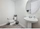 Small, modern half bathroom with gray wood floors, sink, toilet, and a large, circular mirror at 5311 Brydon Woods Cir, St Cloud, FL 34771