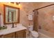 Tiled bathroom featuring a sink, toilet, tub and shower with towel racks and vanity mirror at 5719 Emerson Pointe Way, Orlando, FL 32819