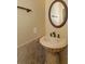 Unique bathroom with a pedestal travertine sink, a round mirror and bronze fixtures at 5719 Emerson Pointe Way, Orlando, FL 32819