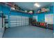 The garage is spacious with blue epoxy flooring, offering ample storage with overhead racks and custom cabinetry at 5719 Emerson Pointe Way, Orlando, FL 32819