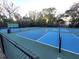 A fenced tennis court complex features blue and green courts against a backdrop of mature trees and vegetation at 621 Daron Ct, Winter Springs, FL 32708