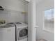 A well-lit laundry room with a washer, dryer, and shelving for storage at 701 Fortanini Cir, Ocoee, FL 34761