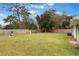 Spacious backyard with lush green grass, mature trees, wooden fence, and playground equipment, ideal for outdoor activities at 704 Baywood Dr, Sanford, FL 32773