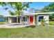Charming single-story home with a covered carport, lush lawn, and a bright red front door at 704 Baywood Dr, Sanford, FL 32773