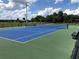 Outdoor blue and green tennis court with dark fencing surrounded by lush green trees at 704 Baywood Dr, Sanford, FL 32773