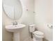 Small half bathroom with pedestal sink, round mirror, and standard toilet at 8941 Rhodes St, Kissimmee, FL 34747