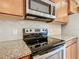 Close-up of a modern range, microwave and granite countertops in a kitchen with wooden cabinetry at 8941 Rhodes St, Kissimmee, FL 34747