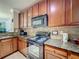 A functional kitchen featuring granite countertops, dark wood cabinets, and stainless steel appliances at 912 Charo Pkwy # 214, Davenport, FL 33897