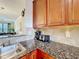 Kitchen showcasing granite countertops, wood cabinets, stainless steel sink, and appliances at 912 Charo Pkwy # 214, Davenport, FL 33897