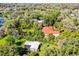 Aerial view of a home with a red roof and a guest house with a screened-in pool surrounded by mature trees at 12002 Mckinnon Rd, Windermere, FL 34786