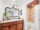Bathroom with a large mirror, granite countertop, dark wood cabinets, and a shower at 12853 Maryland Woods Ct, Orlando, FL 32824