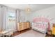 Bright Bedroom featuring a crib, dresser, and playful pink sun accent wall decor at 12853 Maryland Woods Ct, Orlando, FL 32824