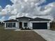 Charming single-story home with a dark gray garage door, a well-manicured lawn, and a welcoming entrance at 13566 Sw 43Rd Cir, Ocala, FL 34473