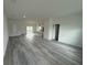 An open-concept living room with light gray flooring, white walls, and a view of the kitchen at 13566 Sw 43Rd Cir, Ocala, FL 34473