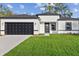 Contemporary home featuring a two-car garage, manicured lawn, and clean, modern black and white design at 13592 Sw 43Rd Cir, Ocala, FL 34473
