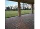 Covered back porch with brick pavers overlooks a lush green lawn and a serene natural backdrop at 17792 Adrift Rd, Winter Garden, FL 34787