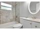 Bathroom with tiled shower and tub, white vanity, and oval mirror providing a clean aesthetic at 1797 31St Nw St, Winter Haven, FL 33881