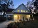 Charming two-story home featuring a covered front porch, carport, and lush landscaping illuminated at twilight at 25704 Aberdovey Ave, Sorrento, FL 32776