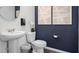 Chic powder room with pedestal sink, elegant fixtures, decorative art, and modern accents against a deep blue wall at 2660 Gouda Dr, Apopka, FL 32703
