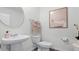 Well-lit powder room with a pedestal sink, modern mirror, and neutral-toned decor with wood-look floors at 2664 Gouda Dr, Apopka, FL 32703