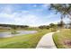 Scenic walking path beside a lake and community homes, surrounded by lush greenery and palm trees at 2738 Norway Maple Ct, Ocoee, FL 34761