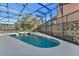 Screened-in pool and hot tub with stone retaining wall, chairs, and lush landscaping at 2801 Lido Key Ct, Kissimmee, FL 34747