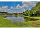 Scenic view of a serene pond reflecting the sky, surrounded by lush greenery and nearby houses at 3180 Pawleys N Loop, St Cloud, FL 34769