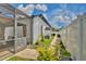 View of a manicured side yard with a brick pathway, potted plants, white fence, and the screened pool area at 3180 Pawleys N Loop, St Cloud, FL 34769
