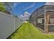 View of the yard featuring a screened lanai, manicured lawn, and white fence at 3180 Pawleys N Loop, St Cloud, FL 34769