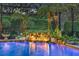 Pool with rock waterfall, accent lighting, and lush tropical landscaping in a screened enclosure at 3358 Fernlake Pl, Longwood, FL 32779