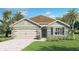 Charming single-story home featuring a two-car garage, stone accents, a well-manicured lawn, and lush tropical landscaping at 33605 Seattle Slew Dr, Sorrento, FL 32776