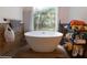 Modern bathroom featuring a freestanding tub, wood-look tile, and bright natural light from the large window at 5646 Spring Run Ave, Orlando, FL 32819