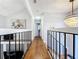 Hallway with hardwood floors, chandelier, and black railings, creating a welcoming atmosphere with a view of the lower level at 5646 Spring Run Ave, Orlando, FL 32819