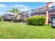 Landscaped backyard featuring a screen-enclosed patio and well-maintained lawn at 5766 Lesabre Dr, Kissimmee, FL 34746