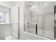 Bright bathroom featuring a shower-tub combo with glass door and white tile surround at 5766 Lesabre Dr, Kissimmee, FL 34746