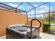 Cozy hot tub under a screened-in patio with privacy walls, perfect for relaxation at 5766 Lesabre Dr, Kissimmee, FL 34746