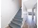 Staircase with grey painted steps, runner, and tiled floors, with view to sliding glass doors to lake at 620 Georgetown Dr # 620, Casselberry, FL 32707