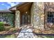 Inviting home entrance with stone columns, wood door, and manicured landscaping at 685 Vistawilla Dr, Winter Springs, FL 32708