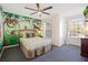 Bedroom featuring custom painted murals, a ceiling fan, and a queen-sized bed with soft bedding at 7902 Silver Bass Ct, Kissimmee, FL 34747
