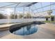 Sparkling pool featuring a waterfall, surrounded by tile and a screened enclosure to enjoy the sunshine at 7902 Silver Bass Ct, Kissimmee, FL 34747