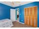 Bedroom with open bathroom door features wood closet and a brightly painted blue wall at 8508 Alveron Ave # 1, Orlando, FL 32817