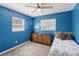 Bedroom with two windows, a ceiling fan and a dresser with storage, blue painted walls at 8508 Alveron Ave # 1, Orlando, FL 32817
