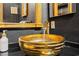 A stylish bathroom features a unique gold colored bowl sink, sleek faucet and black countertops at 8929 Legacy Ct # 106, Kissimmee, FL 34747