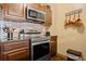 Modern kitchen features stainless steel appliances, including an oven and microwave, with brick backsplash and dark countertops at 8929 Legacy Ct # 106, Kissimmee, FL 34747