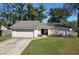 Charming single-story home featuring a stone facade, blue front door, attached garage, and a well-maintained lawn at 103 N Atlas Dr, Apopka, FL 32703