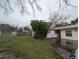 View of the home's side yard, featuring a chain-link fence, lush greenery, and a side entrance at 110 Kasey Dr, Orlando, FL 32807