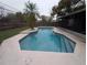 Relaxing in-ground pool with light blue water and a stone border with lush grass and wooden fence at 110 Kasey Dr, Orlando, FL 32807