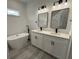 Bright bathroom featuring a standalone tub, dual vanity with black fixtures, and light gray wood-look floors at 171 Marion Oaks Trl, Ocala, FL 34473